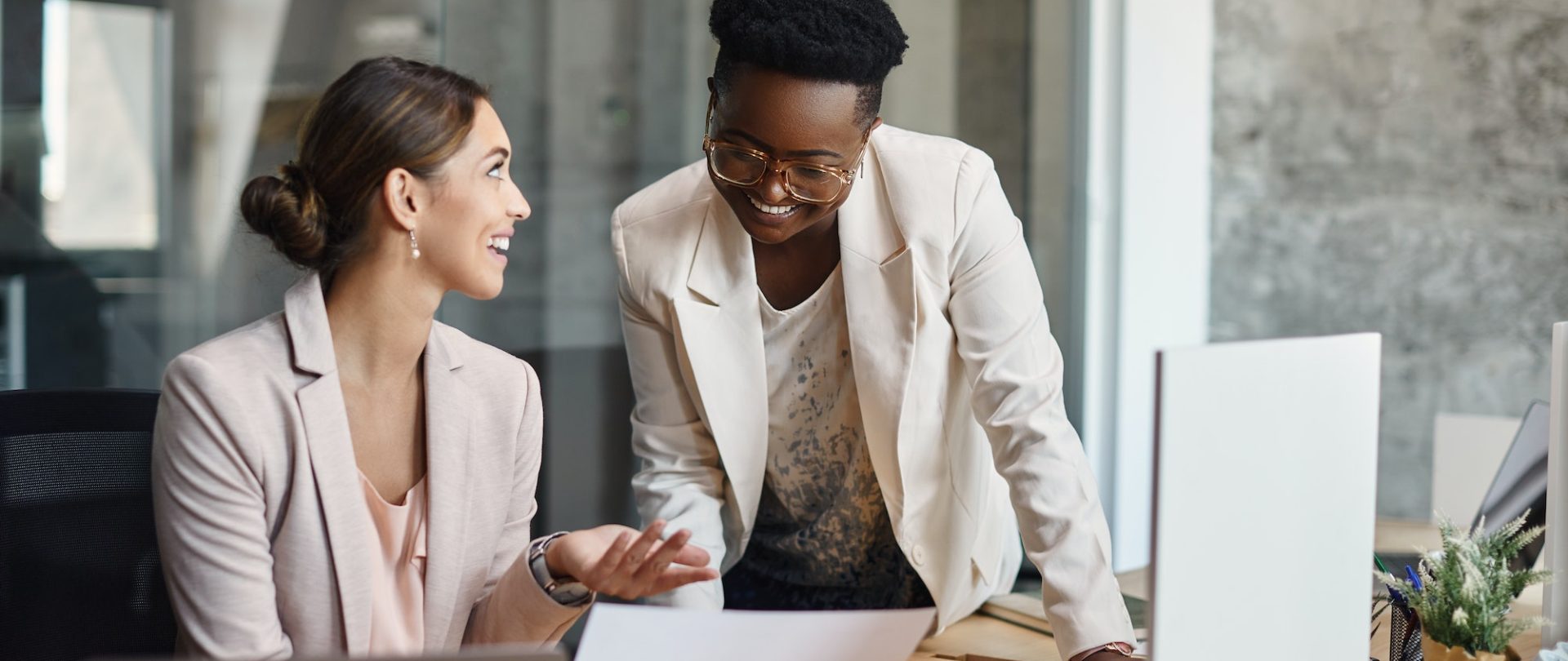 Alegres mujeres de negocios conversando mientras analizan planes y trabajan en la oficina.